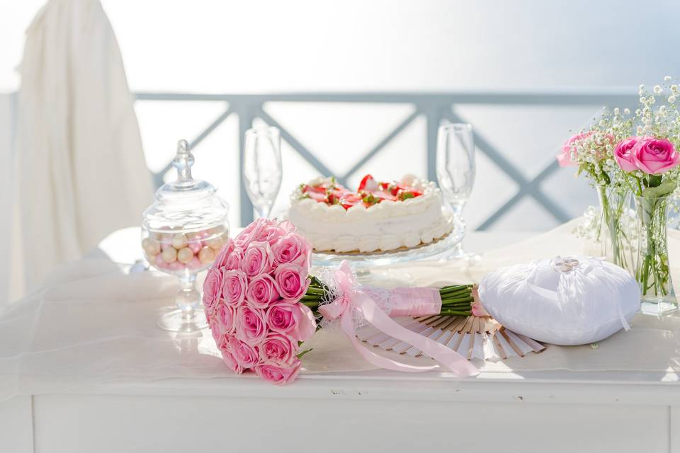 a greek wedding celebration table with a cake and flower bouquet