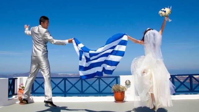 bride and groom holding the greek flag at their wedding
