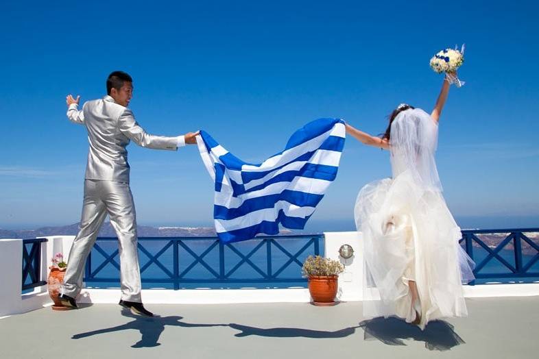 bride and groom holding the greek flag at their wedding