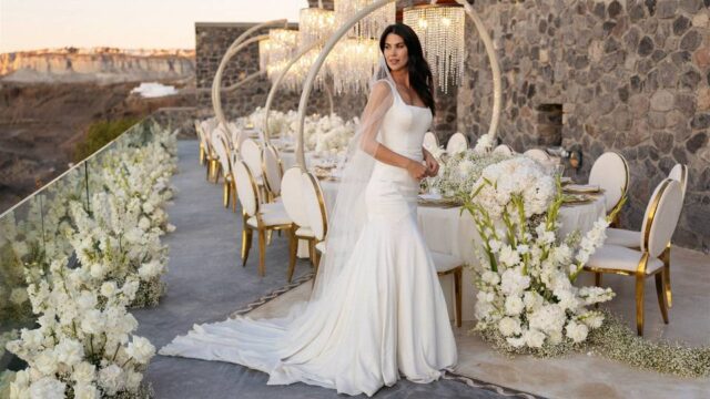 a bride posing in front of flowers and a wedding table at her santorini wedding