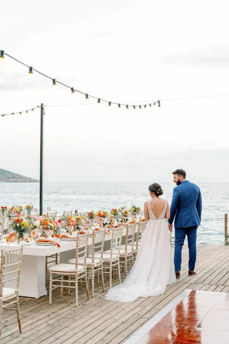 a newlywed couple holding hands admiring the decorations for their greece destination wedding