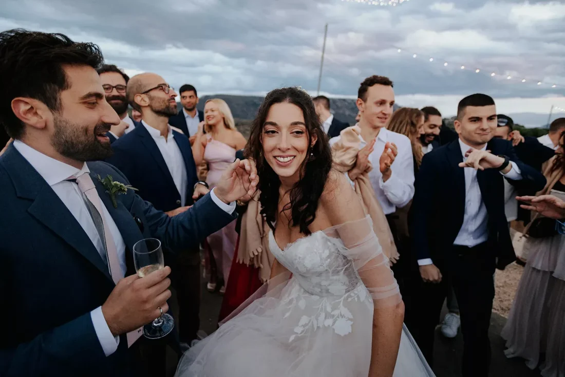 a bride smiling at her greek wedding surrounded by guests