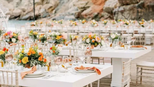 a number of wedding tables set in front of the greek sea and hills