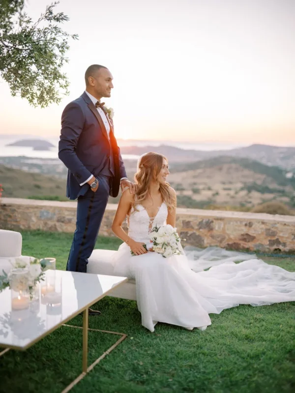 a newlywed couple staring out at the greek hills