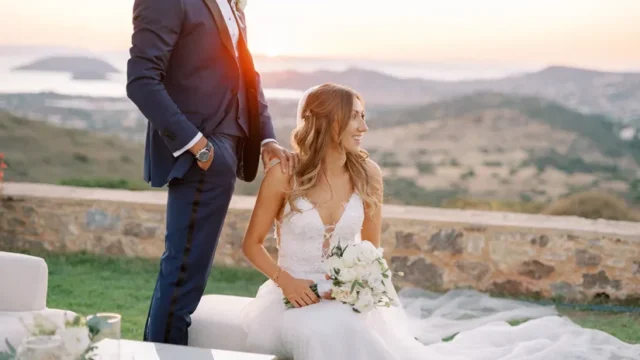 a newlywed couple staring out at the greek hills
