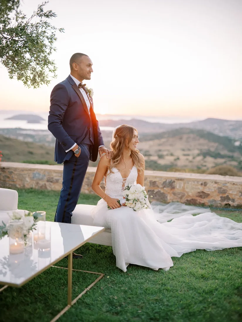 a newlywed couple staring out at the greek hills