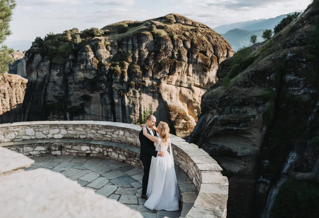 a young newlywed couple embracing in meteora greece on top of a cliff