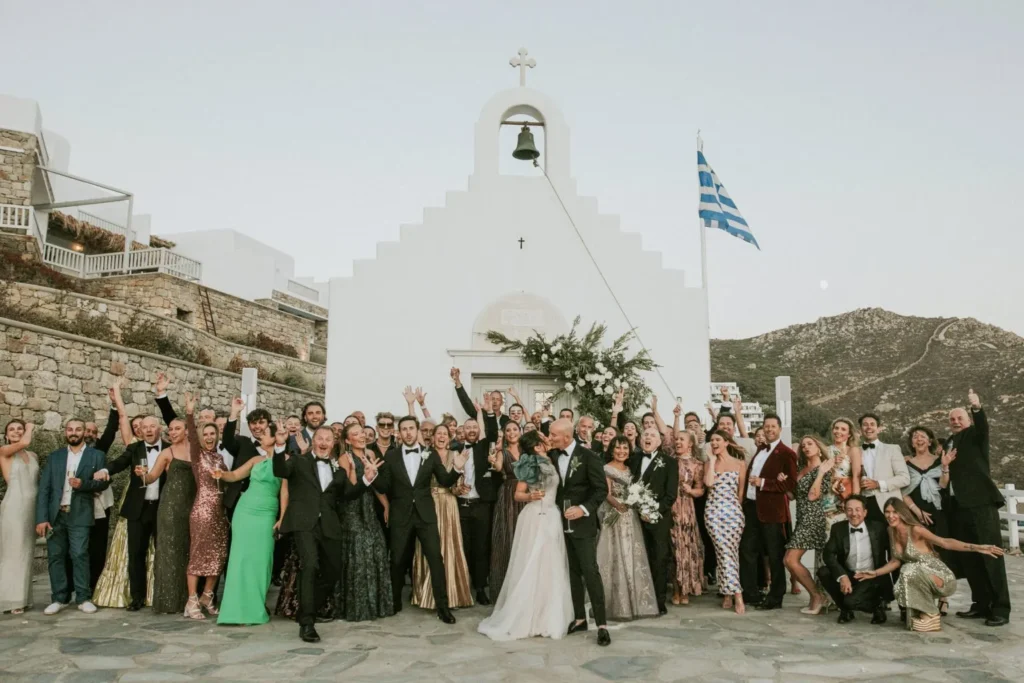 A wedding party in front of a cycladic white chapel getting married in Mykonos