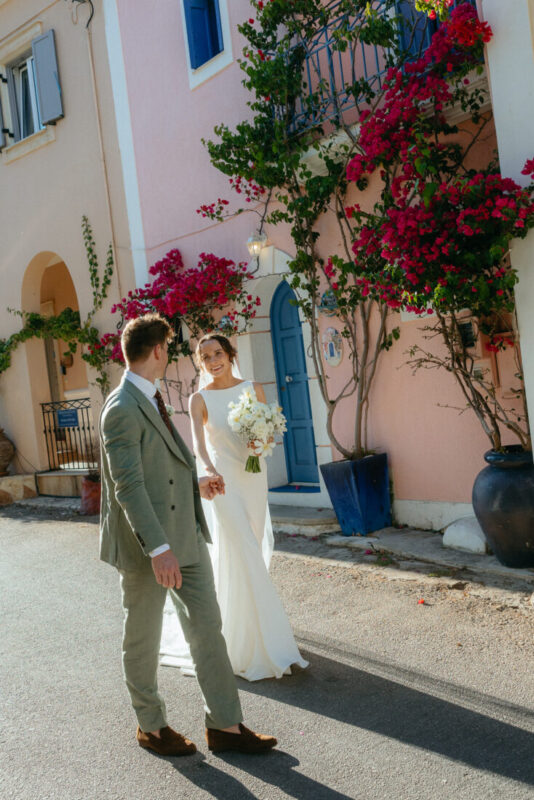 Couple in a village street with bougainvillea and a pastel house behind them
