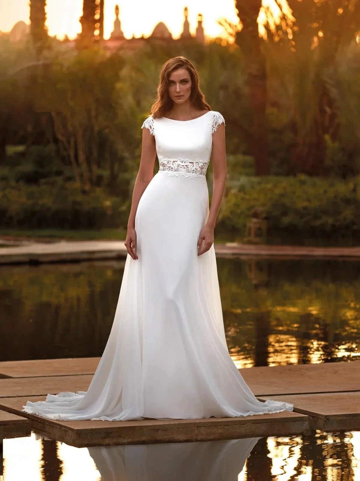 a bride wearing a grecian style wedding dress standing on a pier