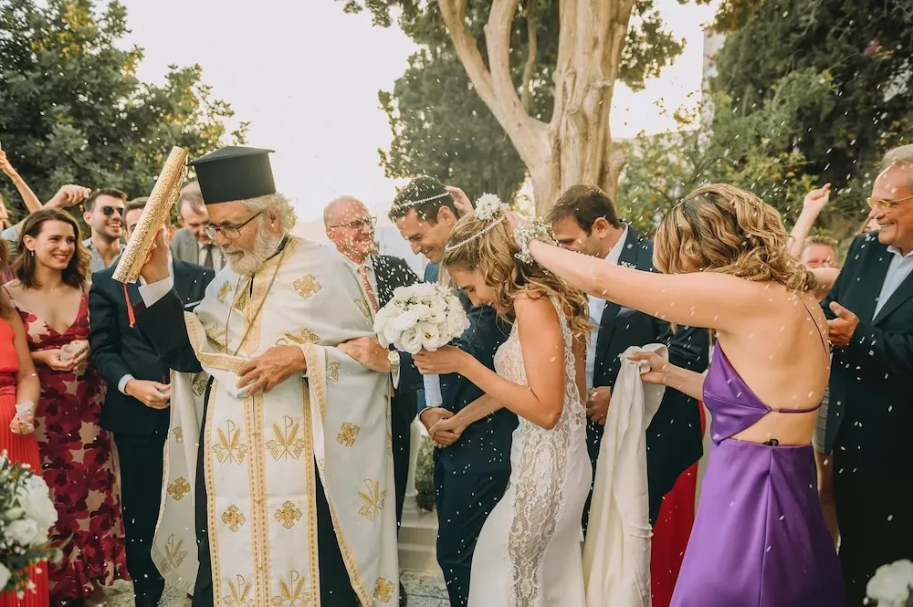 greek orthodox priest is leading a wedding couple during the dance of isaiah