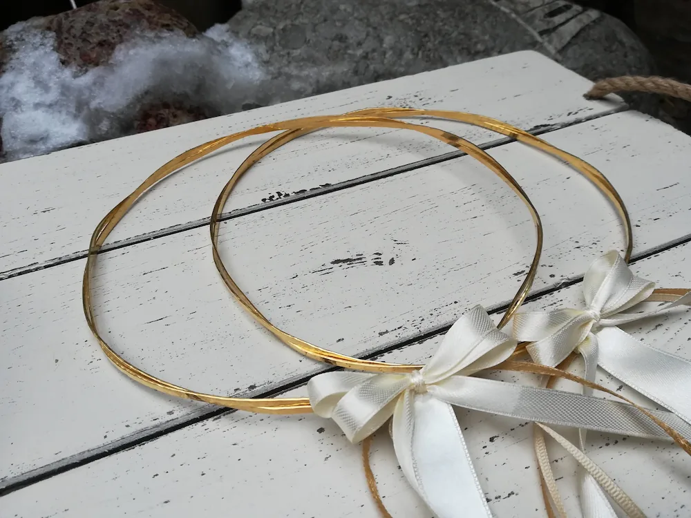 greek wedding stefana crown made from hammered gold with ribbons on a table