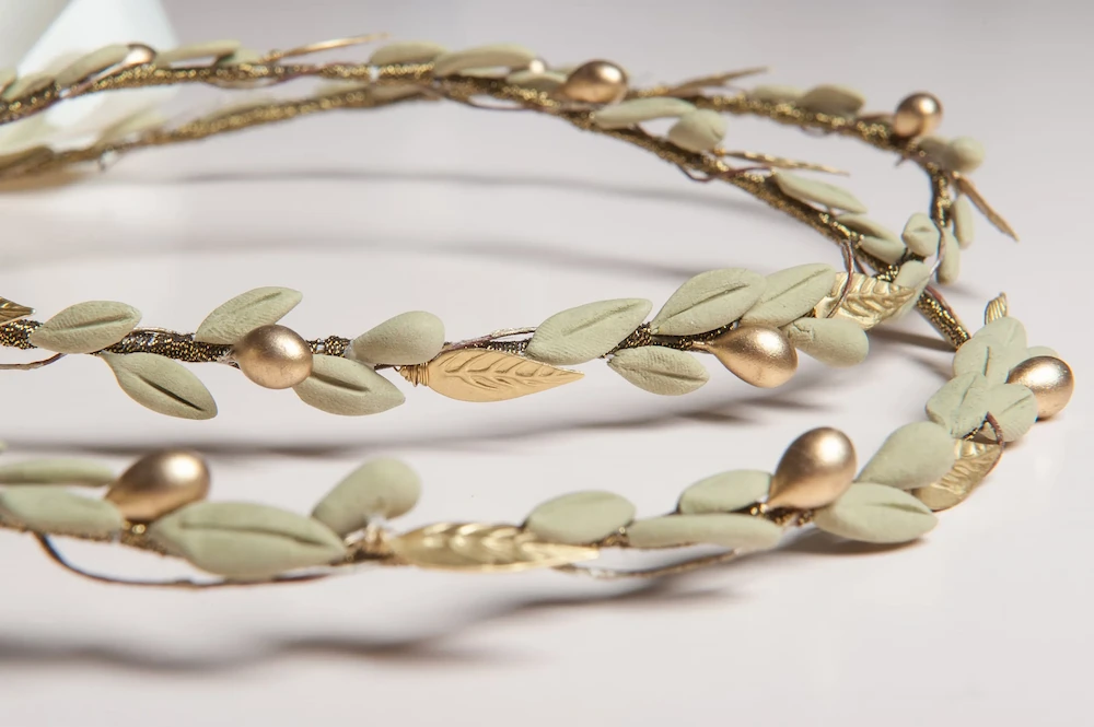 zoomed in picture of a traditional botanical style greek wedding stefana with porcelain olive leaves and gold plated metal