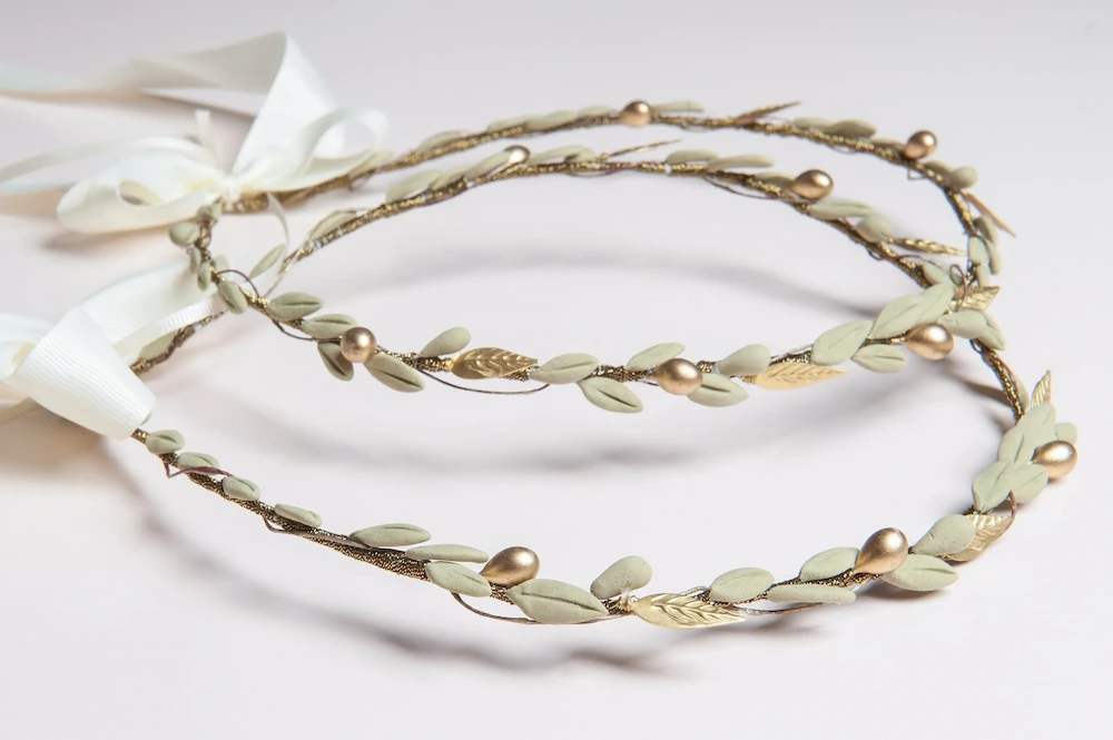 a traditional botanical style greek wedding stefana with porcelain olive leaves and gold plated metal tied with a white ribbon