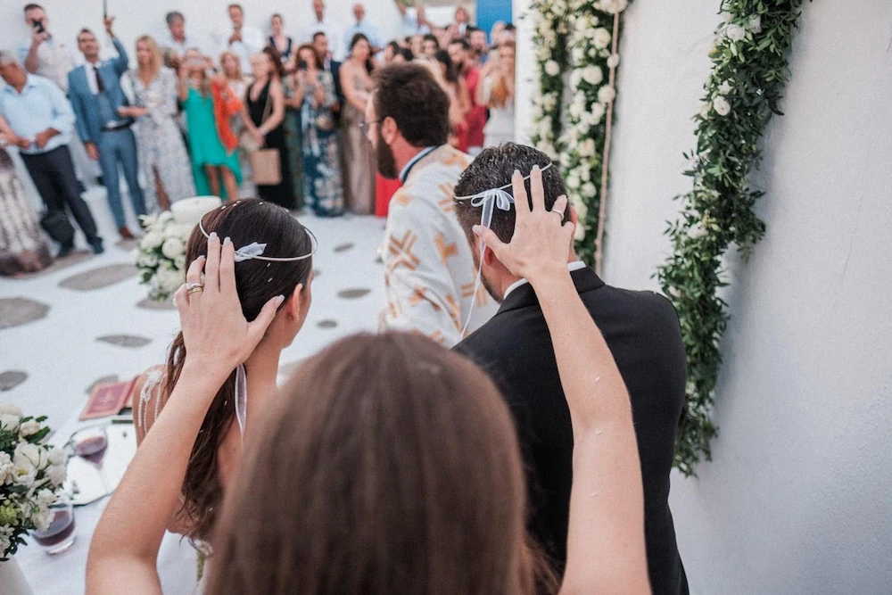 Koumbara holding the stefana above the bride and groom's heads during a Greek Orthodox wedding ceremony