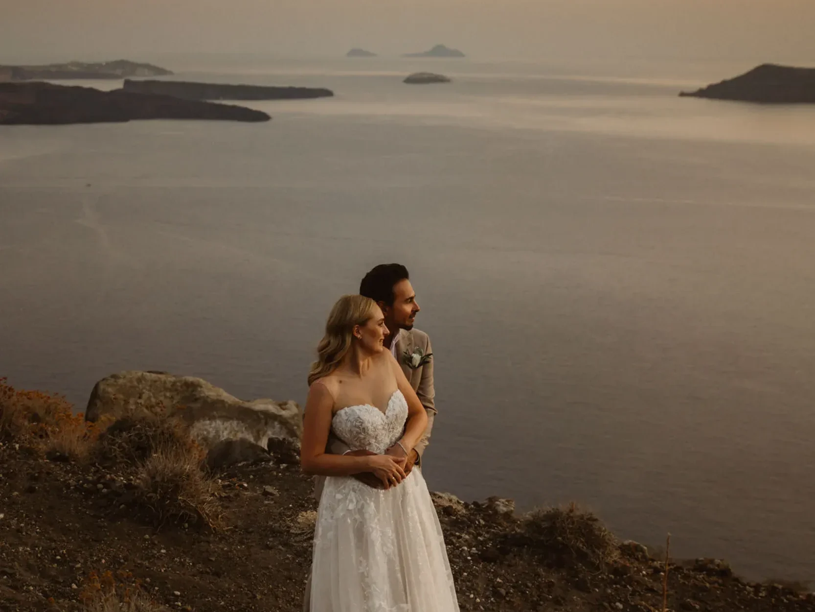 a couple eloping in greece standing on a cliff in santorini