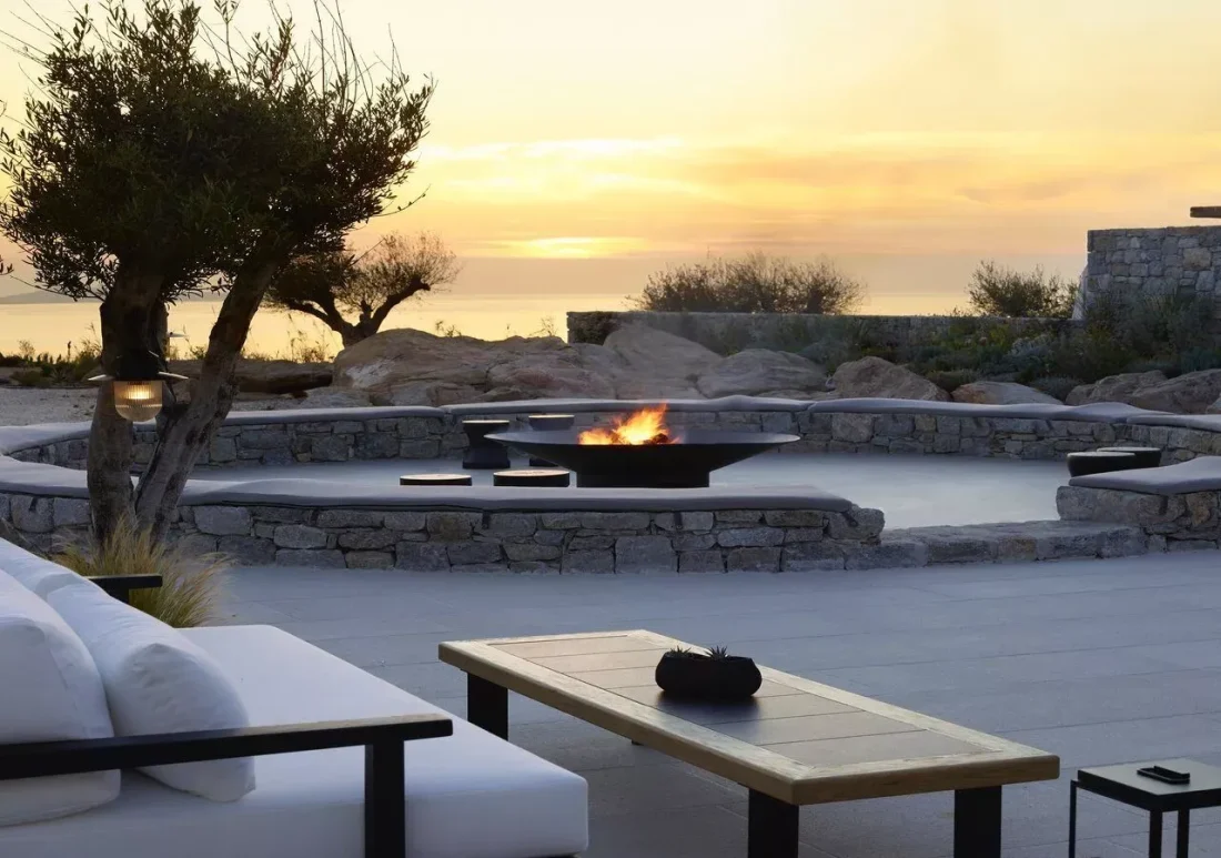 a firepit burns in the evening sunset glow at kalesma mykonos