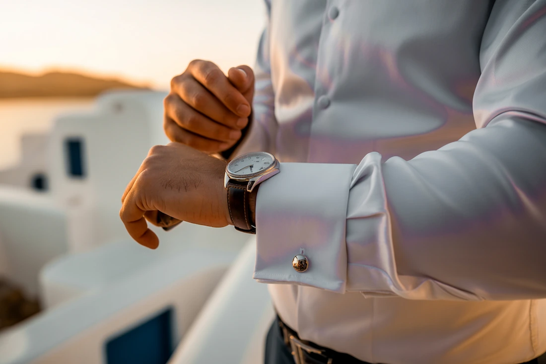 a groom at his wedding in greece checking the time on his watch
