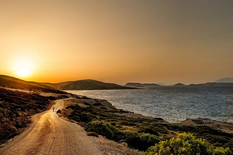A newlywed couple holding hands walking down the road on milos island in greece