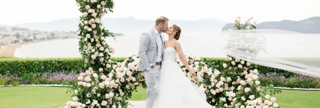 a newlywed couple having their wedding kiss in front of the aegean sea