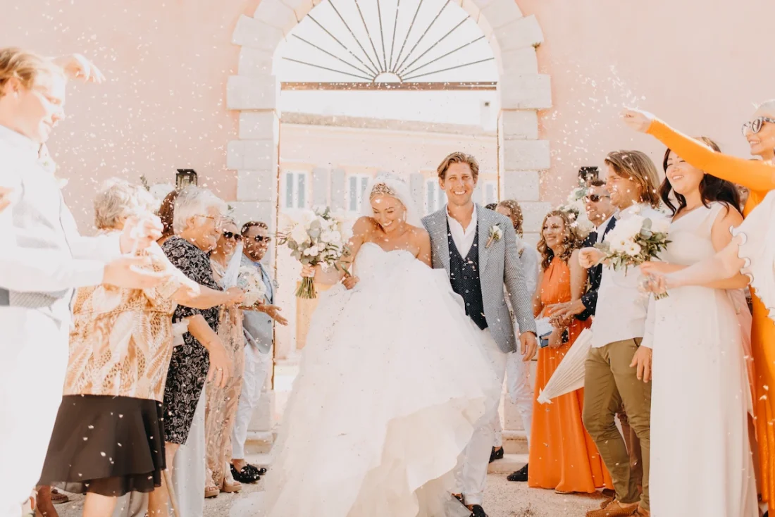 A newlywed couple exiting the courti esate in corfu surrounded by people