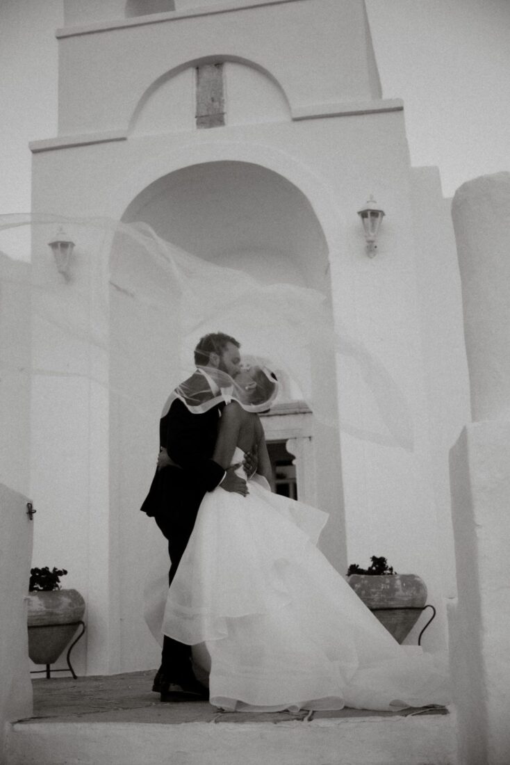 Kendall and Taylor kiss in a whitewashed Sifnos archway