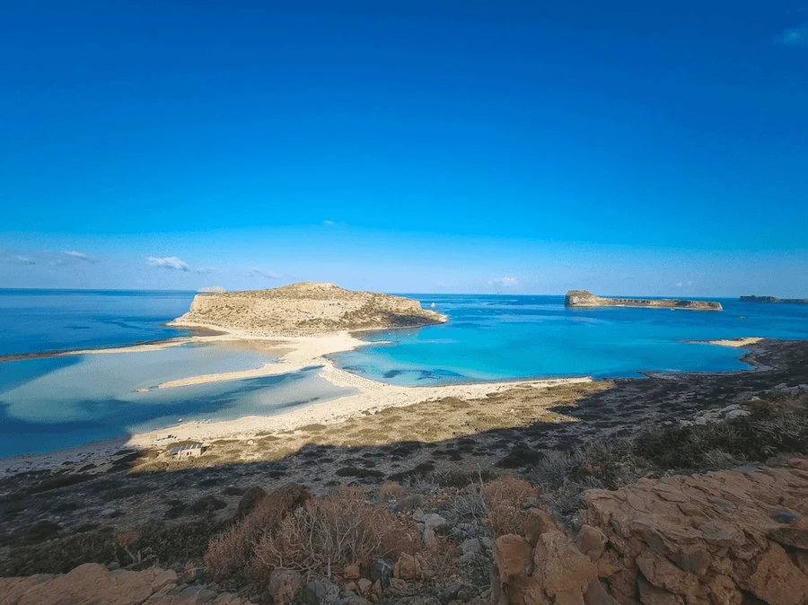 Balos Beach in Crete, its shallow turquoise lagoon and white sand backed by bare hills. Guests fly in for a wedding and stay for views like this, which is part of why they say yes.