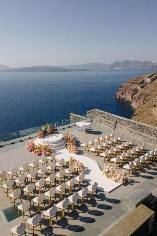 Dining tables set for a wedding above the sea at Cavo Ventus, Santorini