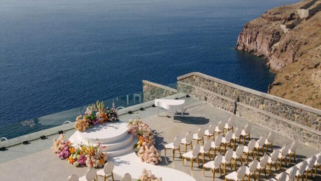Dining tables set for a wedding above the sea at Cavo Ventus, Santorini