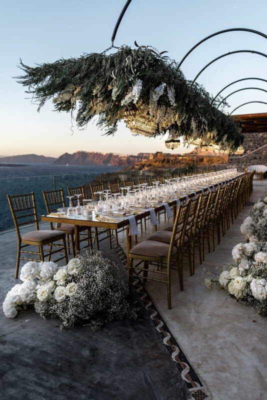 Long dinner table dressed with greenery on the terrace at Cavo Ventus, Santorini