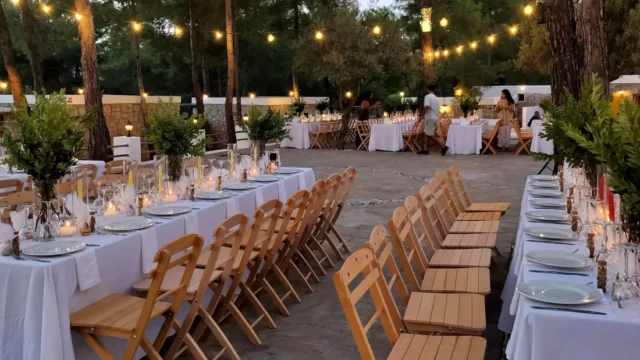 Candlelit tables and wooden chairs among the pines at Kaminari Village, Rhodes