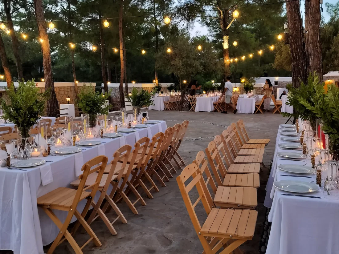 Candlelit tables and wooden chairs among the pines at Kaminari Village, Rhodes