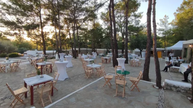 Cocktail tables set out among the pine trees at Kaminari Village, Rhodes