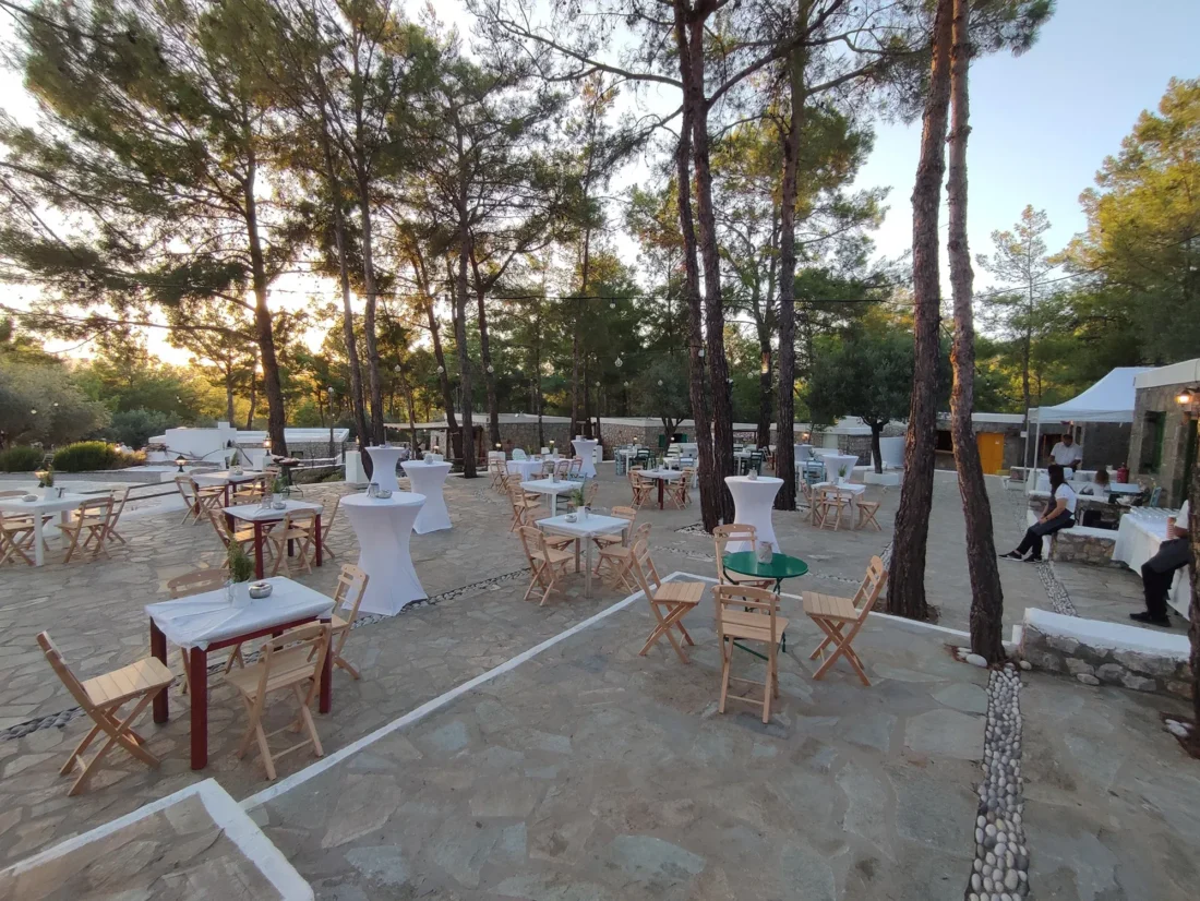 Cocktail tables set out among the pine trees at Kaminari Village, Rhodes