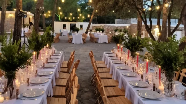 Long banquet table lit by candles under the pines at Kaminari Village, Rhodes