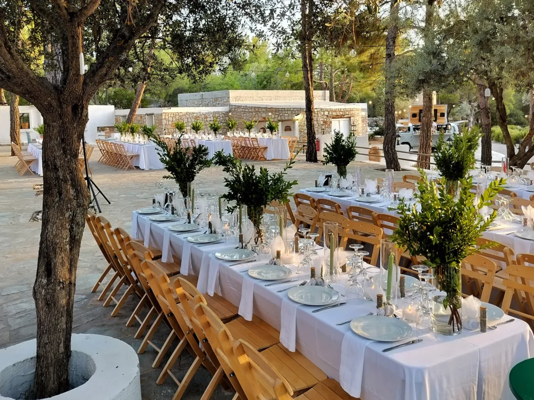 Long tables dressed with olive branches at dusk at Kaminari Village, Rhodes