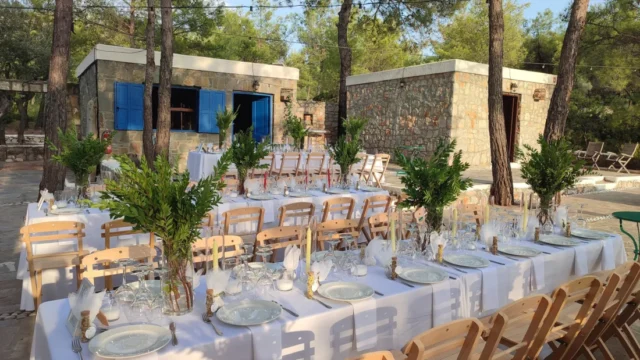 Wedding tables with olive centrepieces beside a stone house at Kaminari Village, Rhodes