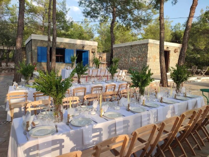 Wedding tables with olive centrepieces beside a stone house at Kaminari Village, Rhodes
