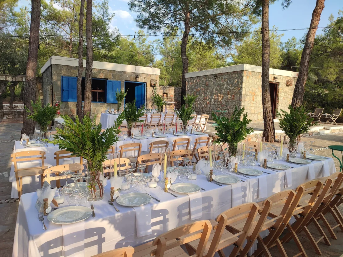 Wedding tables with olive centrepieces beside a stone house at Kaminari Village, Rhodes