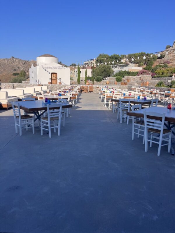 Tables set out on the terrace with the chapel and Lindos beyond at Ktima Lindos