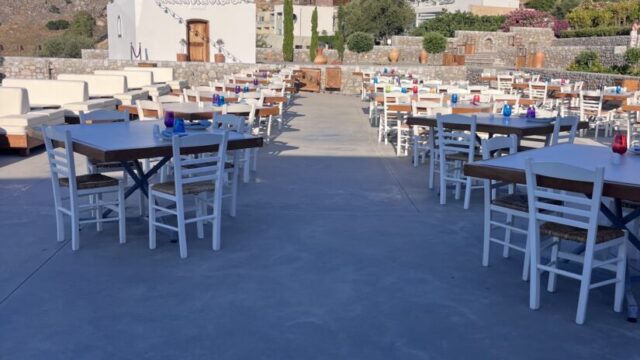 Tables set out on the terrace with the chapel and Lindos beyond at Ktima Lindos
