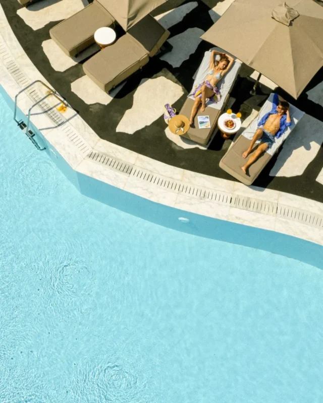 Aerial view of poolside sunbeds and parasols at Royal Myconian, Elia Beach, Mykonos