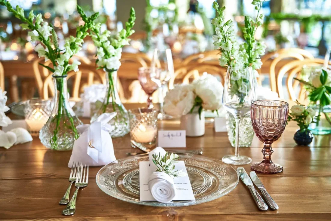 Wedding table setting with white flowers, candles, a name card and glassware at Royal Myconian, Mykonos
