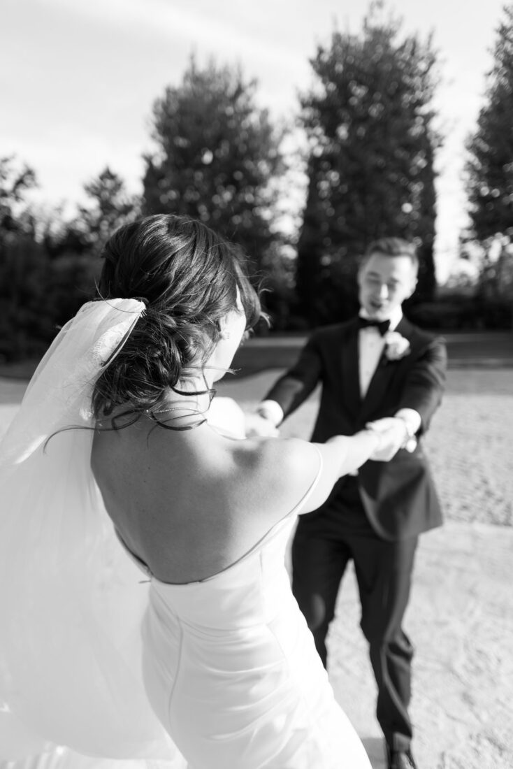 Black and white photo of Garanfil, seen from behind with her veil, holding Roman's hands as they spin