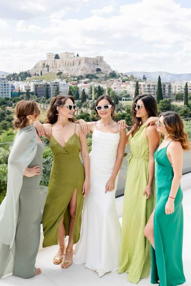 Garanfil and four bridesmaids in green dresses and sunglasses on an Athens rooftop with the Acropolis behind them