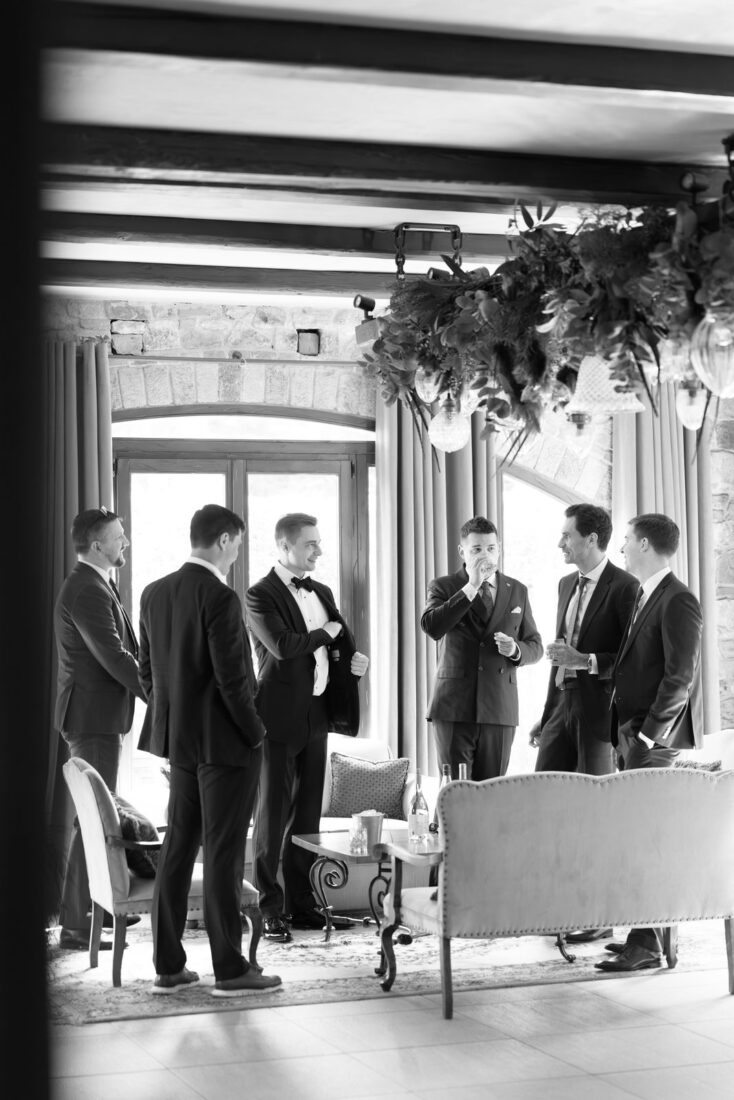 Black and white photo of Roman and his groomsmen talking in a lounge before the wedding