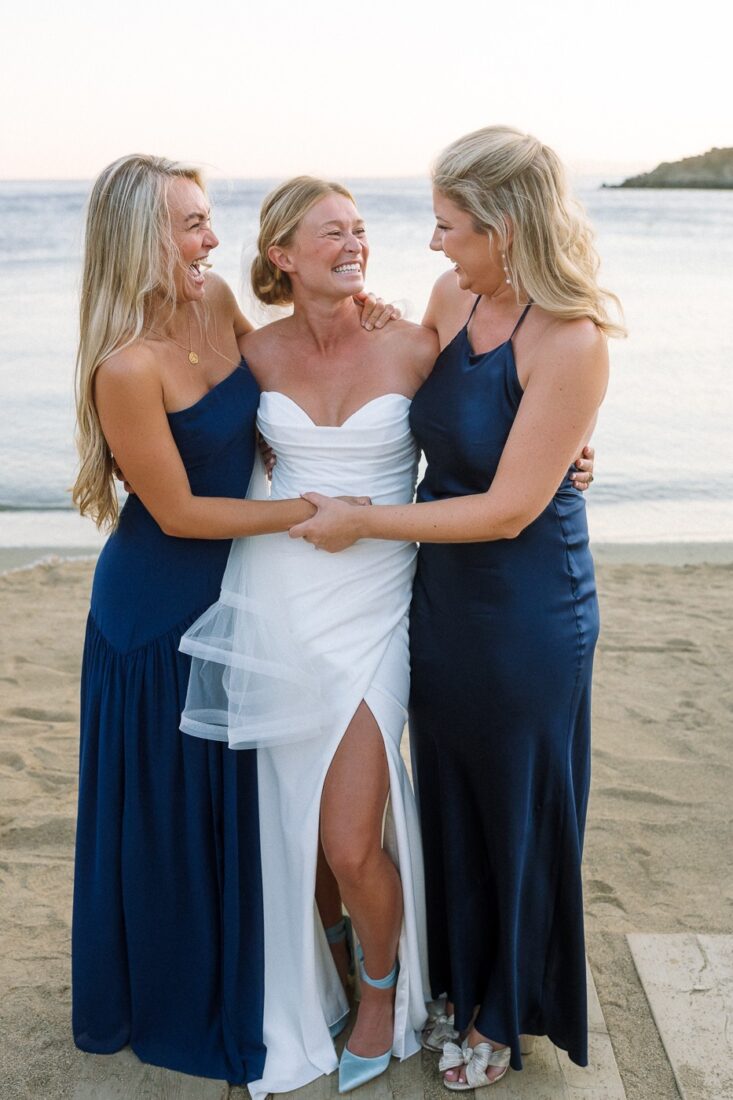 Haley laughing and holding hands with two family members in navy dresses on the beach